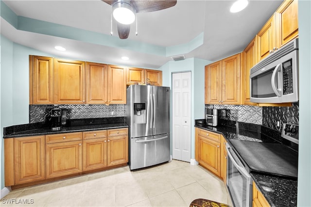 kitchen with tasteful backsplash, appliances with stainless steel finishes, and dark stone counters