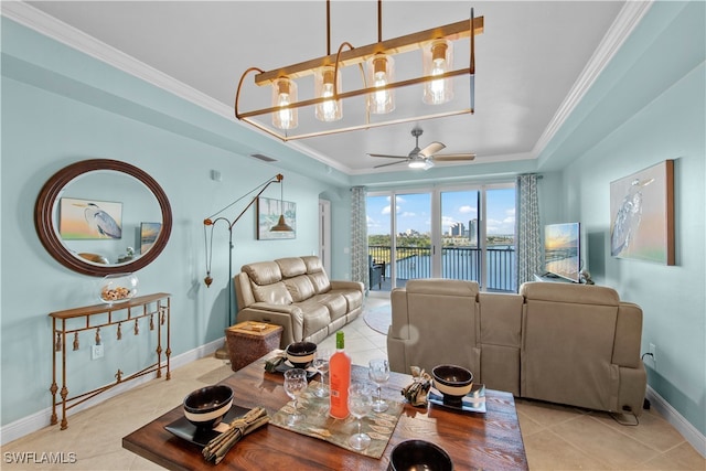 living room with ceiling fan, light tile patterned floors, ornamental molding, and a tray ceiling