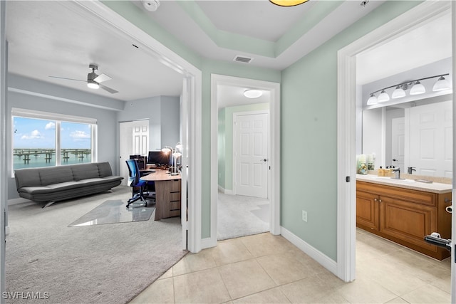 carpeted office with ceiling fan, sink, and a water view