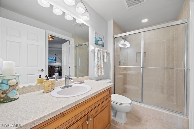 bathroom featuring tile patterned flooring, vanity, an enclosed shower, and toilet