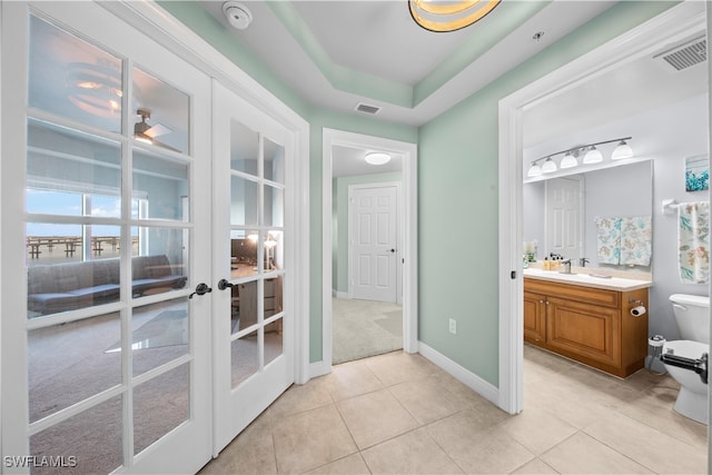 bathroom featuring tile patterned floors, french doors, vanity, and toilet