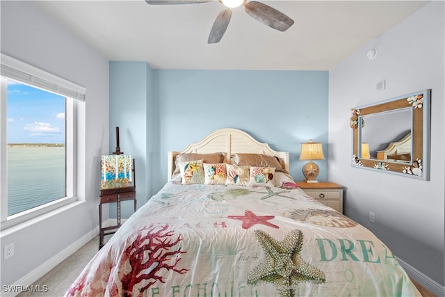 bedroom with carpet floors, ceiling fan, and a water view