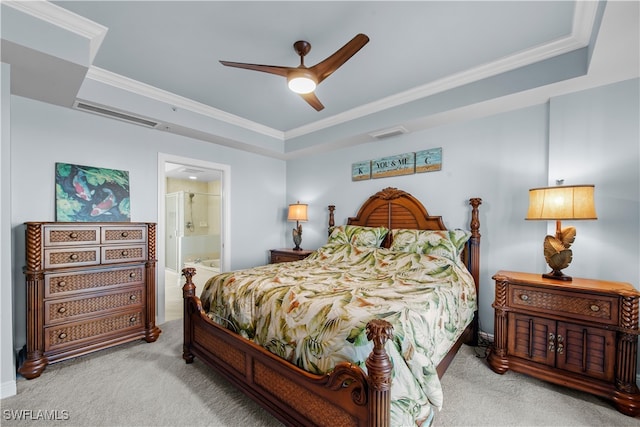 bedroom with a raised ceiling, light colored carpet, ensuite bath, and ceiling fan