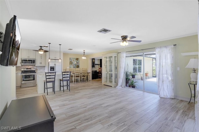 unfurnished living room featuring visible vents, baseboards, light wood-type flooring, and a ceiling fan