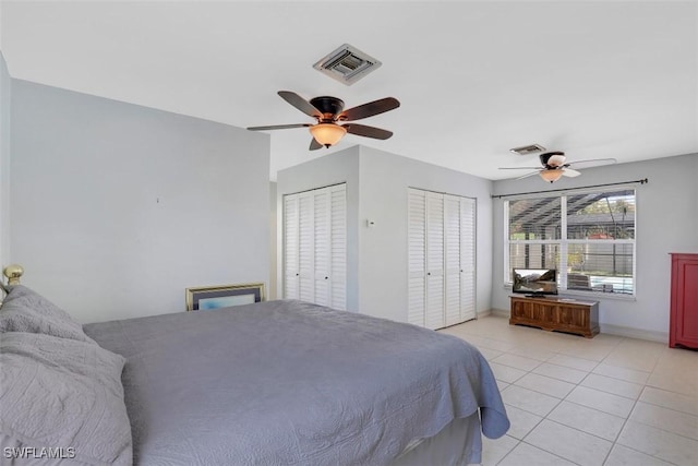 bedroom featuring visible vents, two closets, light tile patterned flooring, and a ceiling fan