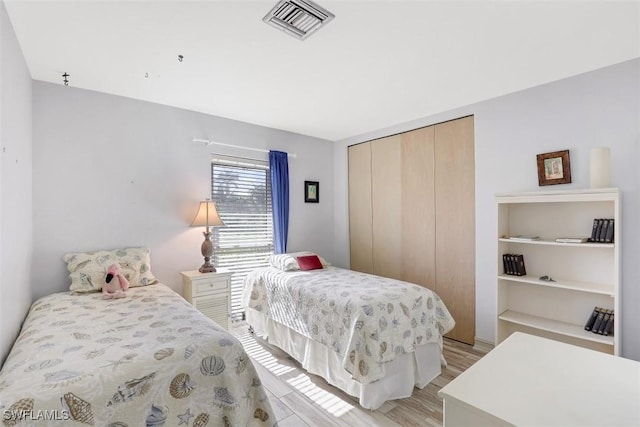 bedroom with a closet, visible vents, and light wood-type flooring