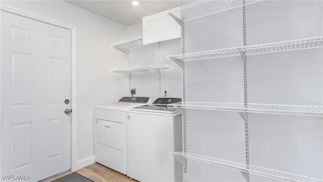 laundry area with light hardwood / wood-style flooring and washer and dryer