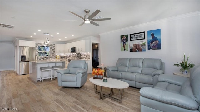 living room with crown molding, light hardwood / wood-style flooring, and ceiling fan