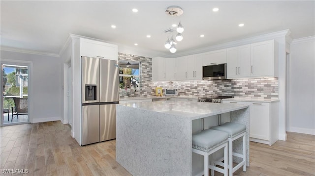 kitchen featuring white cabinets, a kitchen island, stainless steel appliances, and light hardwood / wood-style flooring