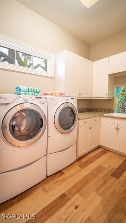 clothes washing area with cabinets, sink, washing machine and dryer, and light hardwood / wood-style flooring