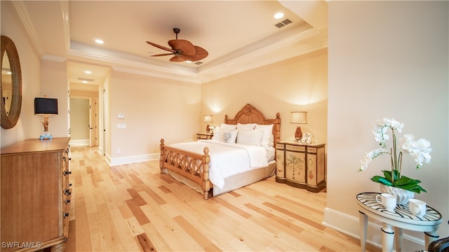 bedroom featuring light hardwood / wood-style floors, a raised ceiling, ceiling fan, and crown molding