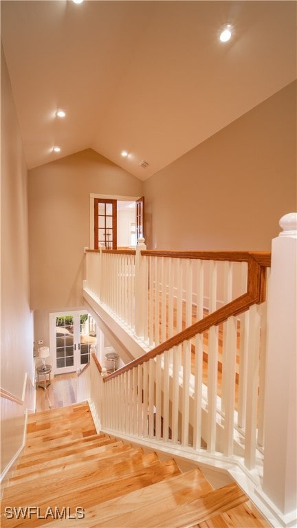 stairway with wood-type flooring, a wealth of natural light, french doors, and lofted ceiling