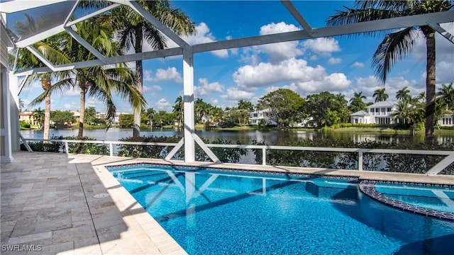 view of pool with an in ground hot tub, a patio, a water view, and glass enclosure