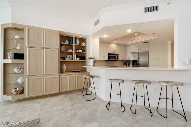 kitchen featuring kitchen peninsula, appliances with stainless steel finishes, a kitchen bar, and crown molding