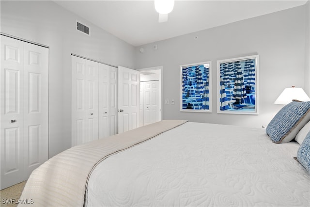 bedroom with carpet, ceiling fan, and multiple closets