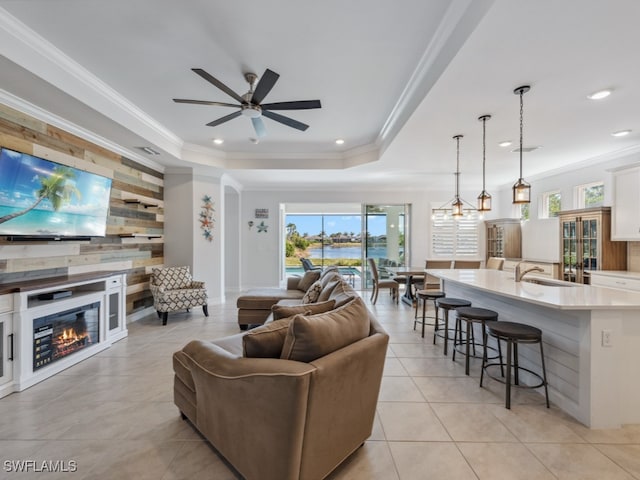 living room featuring plenty of natural light, ceiling fan, ornamental molding, and sink