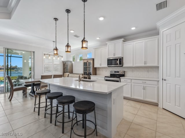 kitchen featuring white cabinets, appliances with stainless steel finishes, and a center island with sink