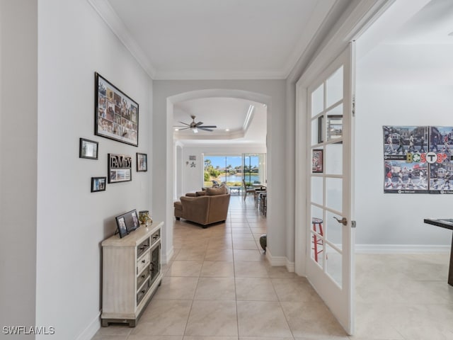 hallway with light tile patterned floors, a raised ceiling, french doors, and ornamental molding