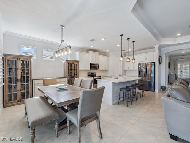 dining space featuring sink, light tile patterned floors, a healthy amount of sunlight, and ornamental molding