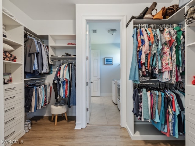 spacious closet featuring independent washer and dryer and light hardwood / wood-style floors