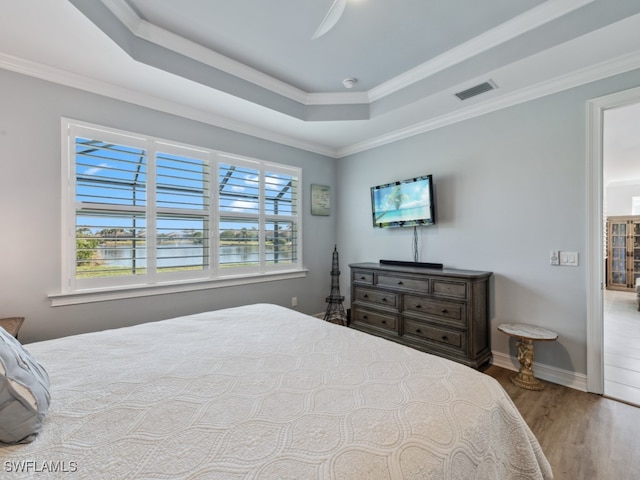 bedroom with a raised ceiling, crown molding, hardwood / wood-style floors, and ceiling fan