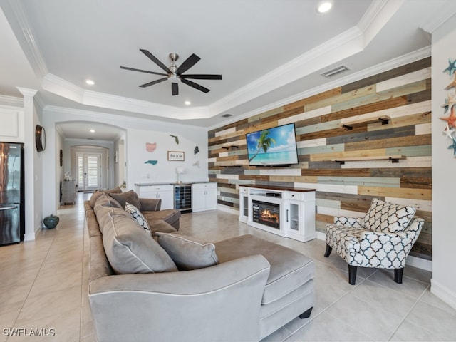 tiled living room with a raised ceiling, beverage cooler, and ornamental molding