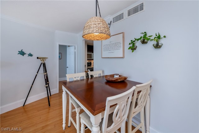 dining room with crown molding and light hardwood / wood-style flooring