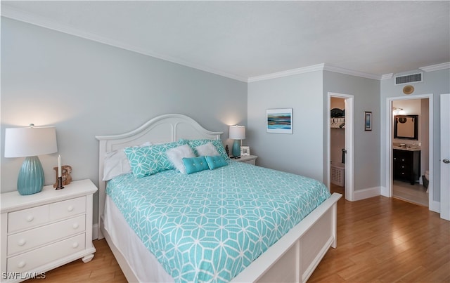 bedroom featuring light hardwood / wood-style flooring, ensuite bath, and ornamental molding