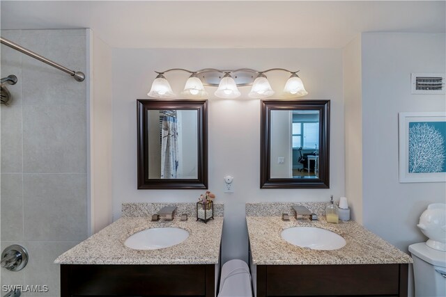 bathroom with a tile shower, vanity, and toilet