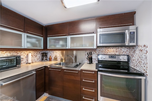 kitchen with decorative backsplash, appliances with stainless steel finishes, dark brown cabinets, and sink