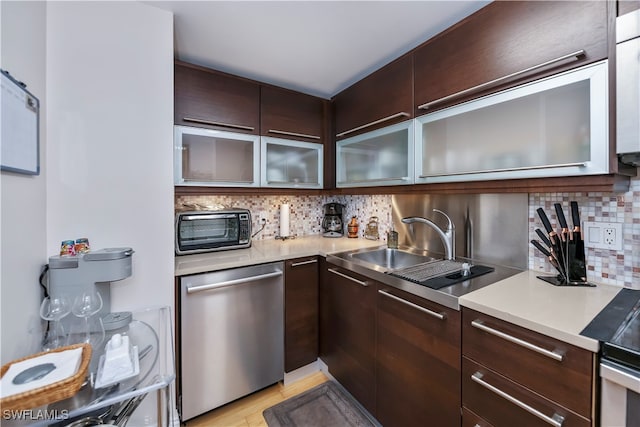 kitchen featuring dishwasher, sink, decorative backsplash, dark brown cabinets, and light wood-type flooring