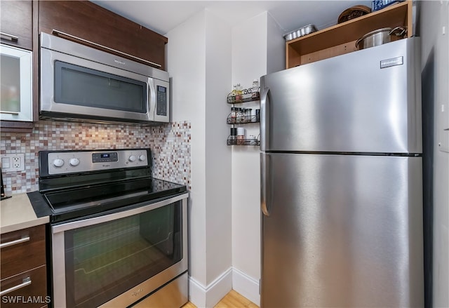 kitchen with decorative backsplash, light wood-type flooring, dark brown cabinetry, and stainless steel appliances