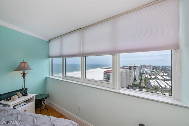 bedroom featuring a water view, ornamental molding, and wood-type flooring