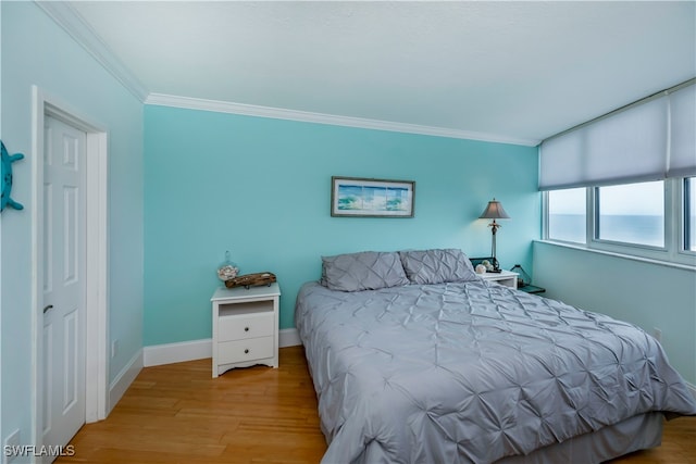 bedroom featuring crown molding and light hardwood / wood-style flooring