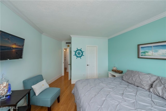 bedroom featuring a textured ceiling, light wood-type flooring, and crown molding