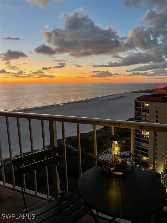 balcony at dusk with a beach view and a water view