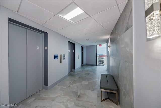 hall with a paneled ceiling and elevator