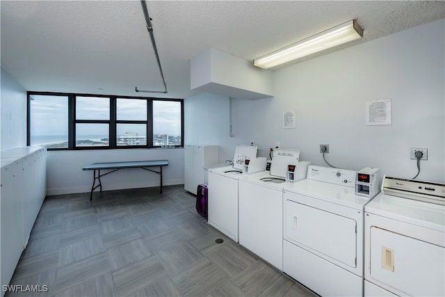 clothes washing area with independent washer and dryer and a textured ceiling