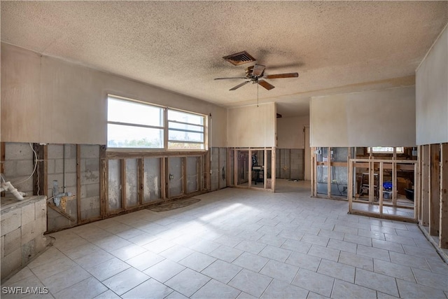 empty room with ceiling fan and a textured ceiling