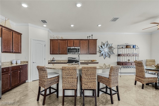 kitchen featuring a kitchen bar, a center island with sink, ornamental molding, and appliances with stainless steel finishes