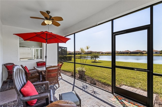 sunroom / solarium with ceiling fan and a water view