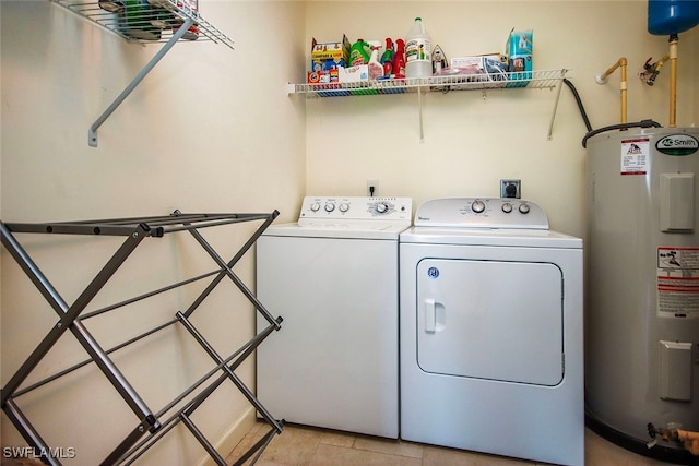 laundry room with water heater, washer and clothes dryer, and light tile patterned flooring