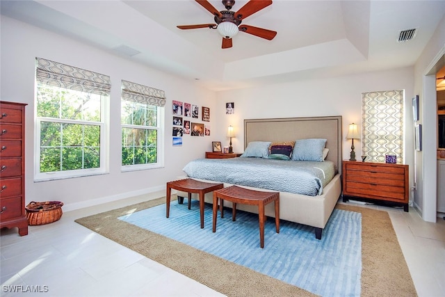 bedroom with ceiling fan and a raised ceiling