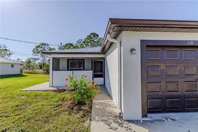 view of exterior entry with a yard and a garage