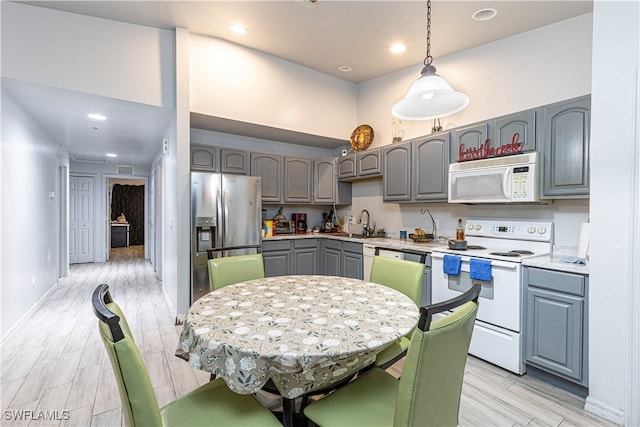 kitchen featuring gray cabinetry, stainless steel appliances, sink, decorative light fixtures, and light hardwood / wood-style flooring