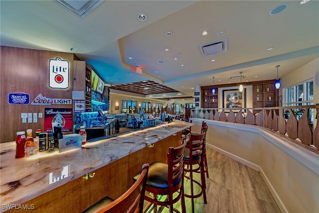 bar with hanging light fixtures and light hardwood / wood-style flooring