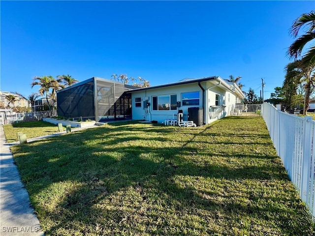 back of house featuring a yard and glass enclosure