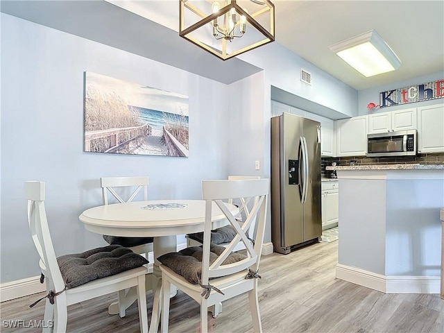 dining space with light hardwood / wood-style flooring and a chandelier