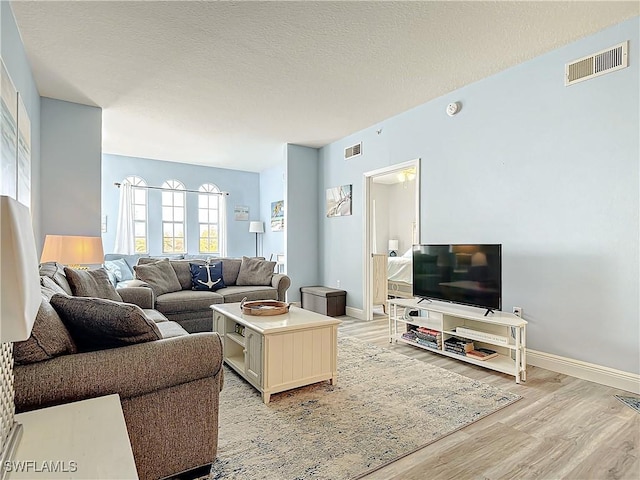 living room featuring light hardwood / wood-style flooring and a textured ceiling