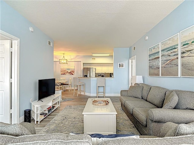 living room with hardwood / wood-style floors, a notable chandelier, and a textured ceiling